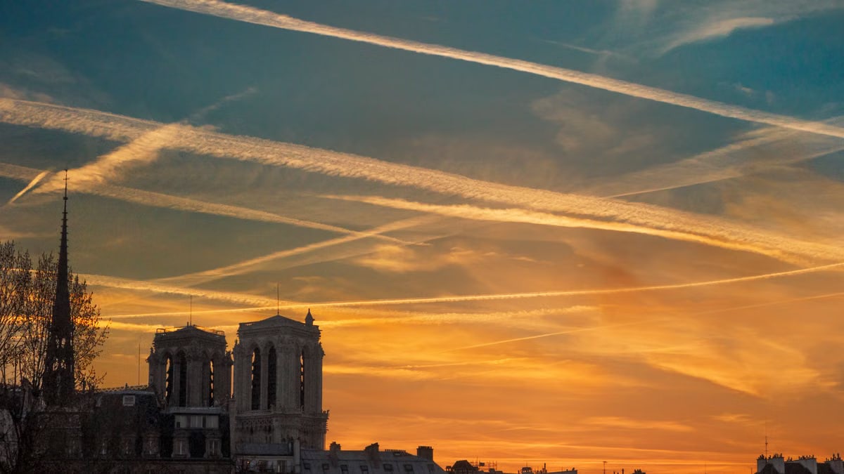 Capture of a dramatic sunset over Notre-Dame Cathedral in Paris with an orange sky.